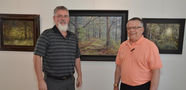 Dr. John Chowning, left, talks with Bill Guffey, an artist from Cumberland County, which is  Chowning's native home. They were discussing the middle painting, Chowning's favorite. The art work will be on display at the Pence-Chowning Art Gallery, 205 University Drive, through  Sept. 12. The Pence-Chowning Art Gallery is named after Chowning, vice president for church  and external relations andexecutive assistant to the president at Campbellsville University,  and his wife, Cathy Pence Chowning. (Campbellsville University Photo by Joan C.  McKinney)